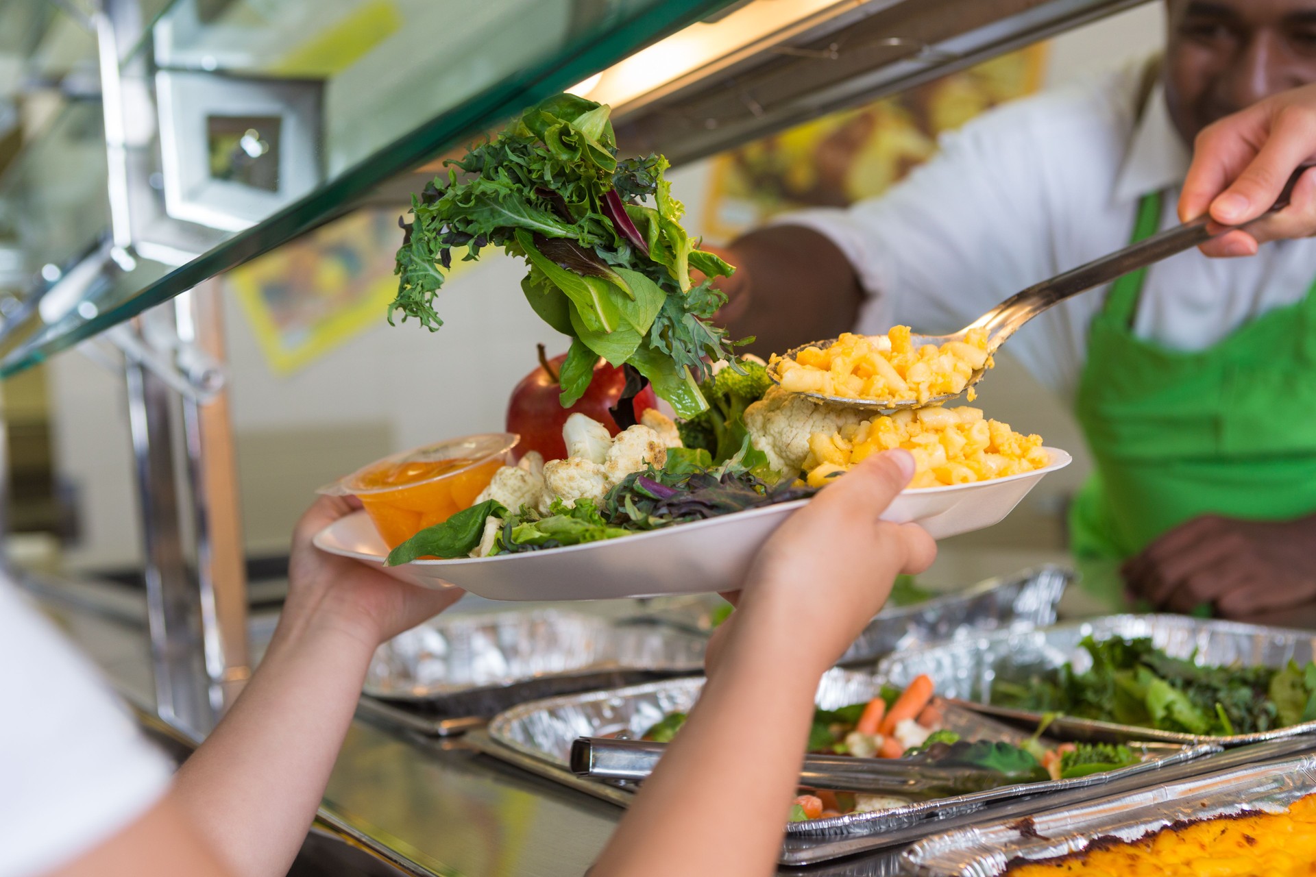 Cafeteria worker serving healthy food to elementary school students